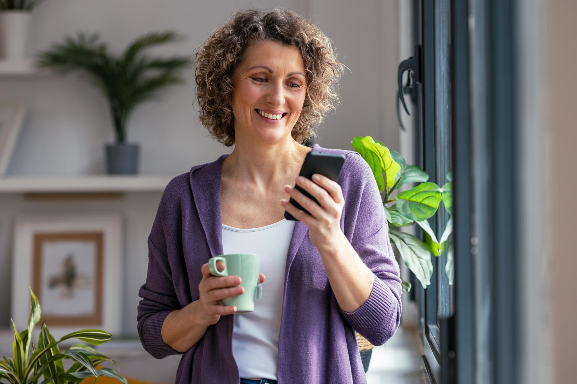female-european-adult-indoor-using-her-mobile-phone-while-drinking-coffee-web (1)