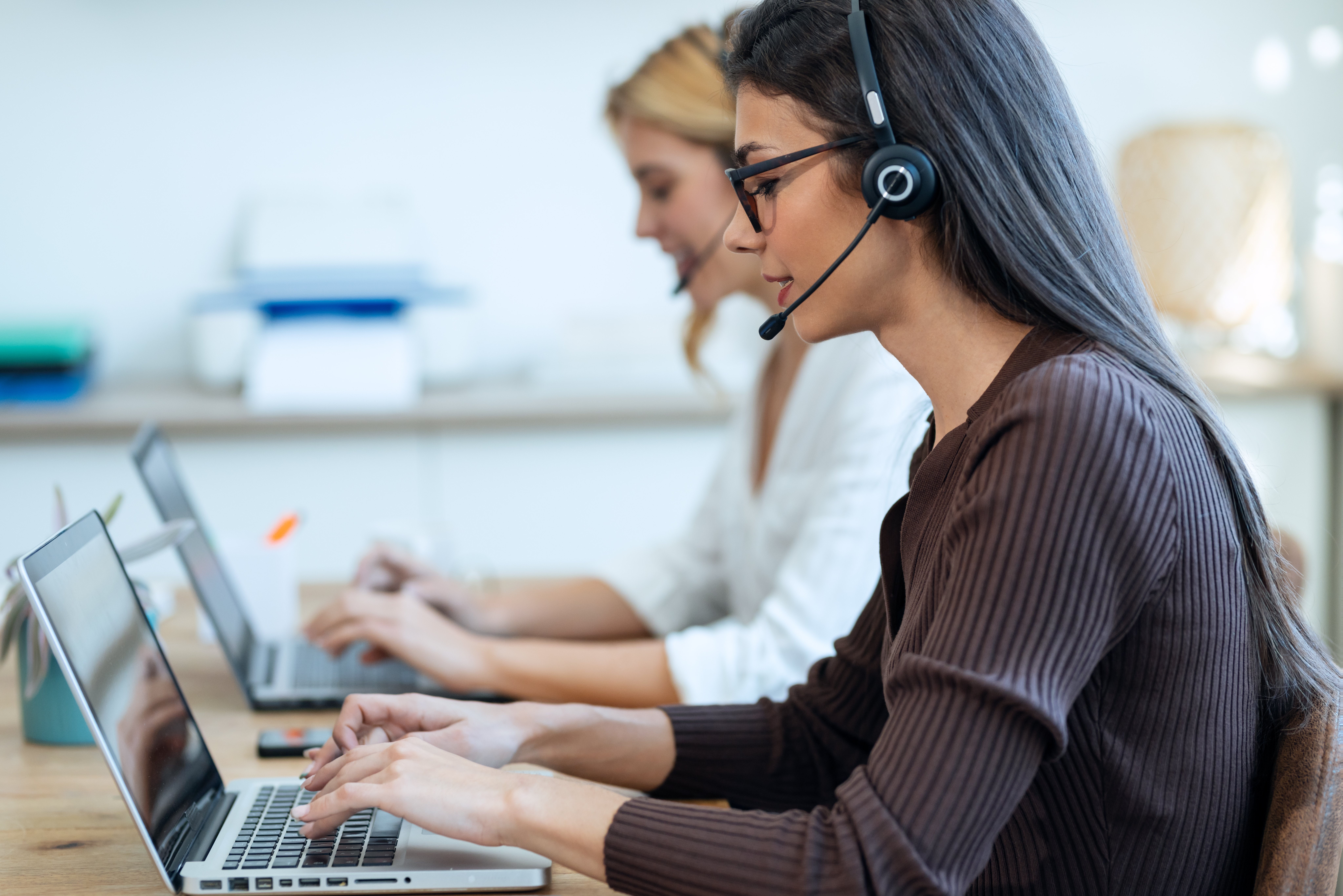 female-european-adult-secretary-receptionist-talking-while-typing-on-laptop-web (1)