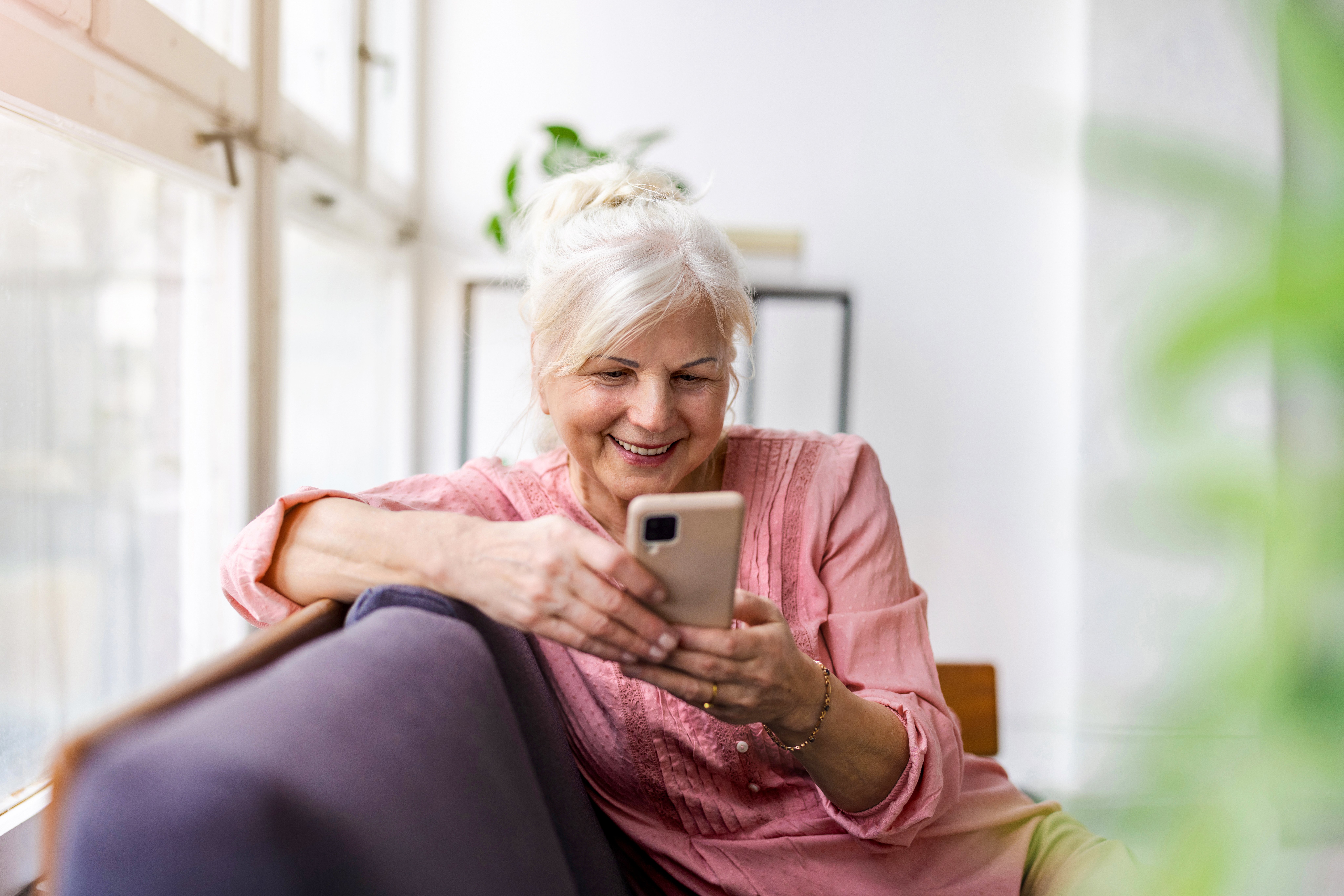 female-european-elderly-indoor-using-smartphone-sitting-on-sofa-web