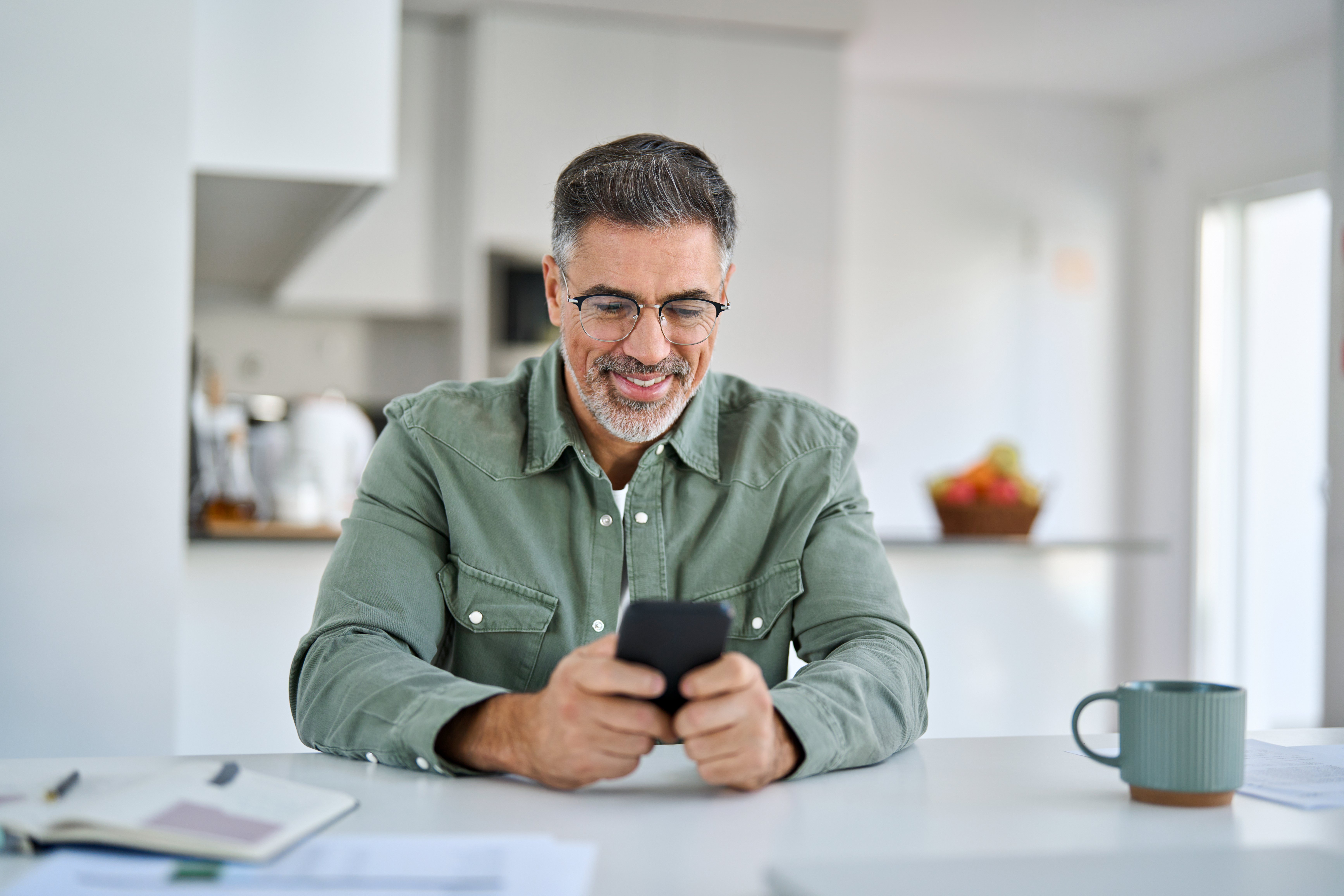 male-european-adult-patients-using-mobile-phone-at-kitchen-table-at-home